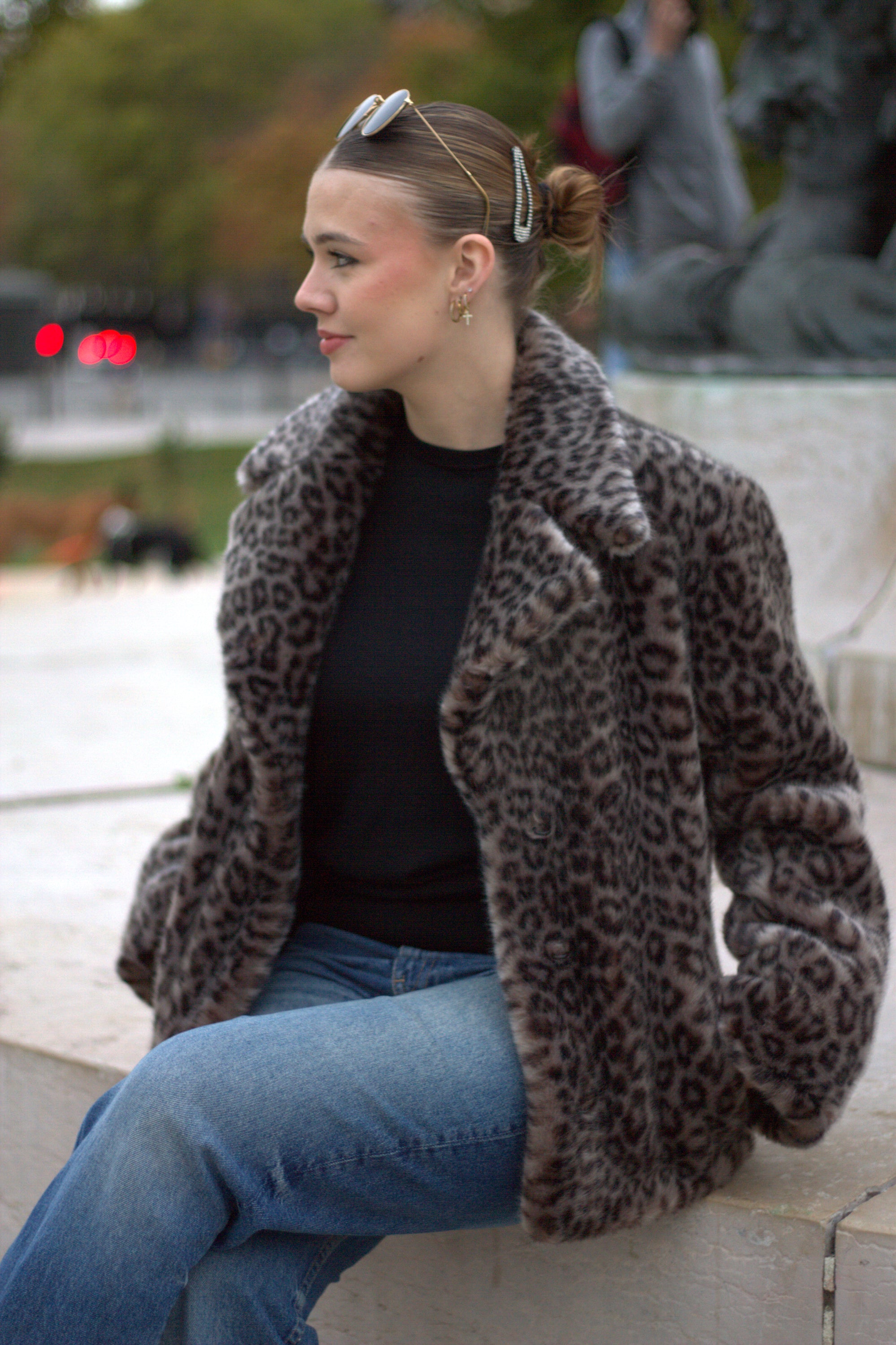 Vestes en léopard fourrure vegan Romy portée par une femme assise représentant la veste Romy